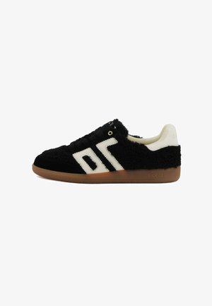 Sneaker low-top con texture nera fuzzy, design geometrico bianco sui lati, tallone bianco, lacci neri e suola in gomma color crema.