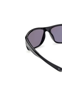 Schwarze Sonnenbrille mit einem eleganten, glänzenden Rahmen; gewölbte Gläser mit einem leichten Farbverlauf; mit einem dezenten Logo am Bügel.