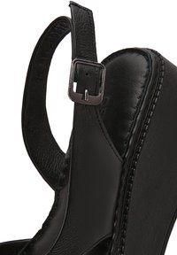Zwarte leren wedge sandaal met een ronde neus, verstelbare enkelband met metalen gesp en een gestructureerde zoolrand voor grip.