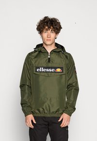 Žalios spalvos vandeniui atspari striukė su pusiau užtrauktuku, elastingais rankogaliais ir dideliu priekiu kišeniu su juodu "ellesse" logotipu ir spalvinga grafika.