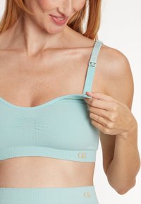 Gaiši zils ribots bralette ar regulējamām siksnām un bezšuvju dizainu. Iekļautas logotipa akcenti apakšā un teksturēta apdare.