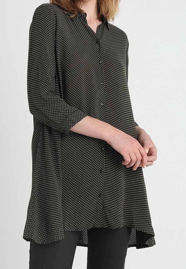 Blusa nera con bottoni, a pois bianchi, maniche a tre quarti, orlo curvo, tessuto morbido e vestibilità ampia.