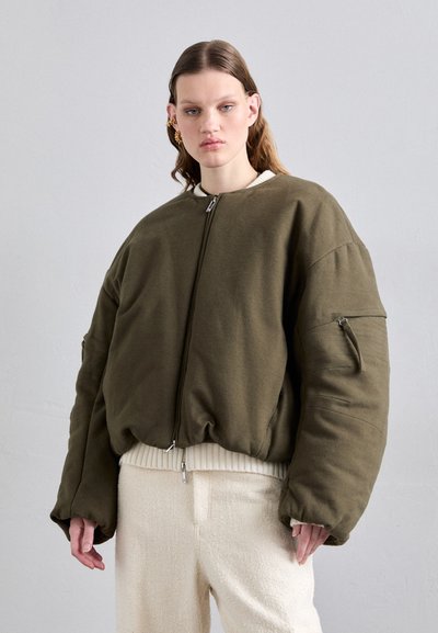 Giubbotto bomber verde oliva con zip frontale, orlo a coste e maniche oversize. Tessuto testurizzato con tasca laterale e cuciture evidenti.