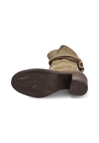 Vihreät mokkanahkasaappaat nilkkapituisina, ruskealla nahkakiinnityshihnalla, neliskulmaisella varpaalla ja teksturoidulla tummanruskealla pohjalla. Varusteena on kasattu korko.