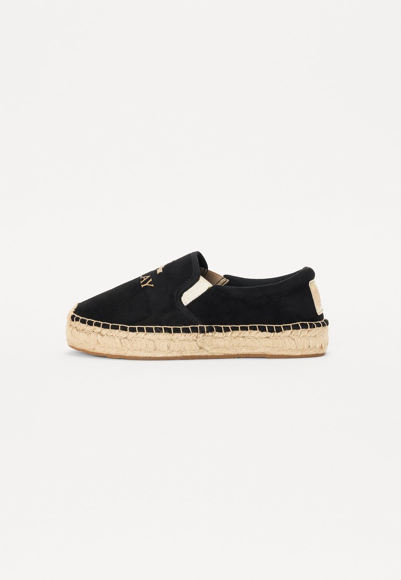 Black suede slip-on shoes with natural jute outsole, featuring stitch detailing and a textured upper. Accentuated with a logo on the front.