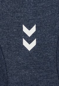 Zwei weiße nach unten zeigende Chevron-Muster auf strukturiertem dunkelblauem Strickstoff.