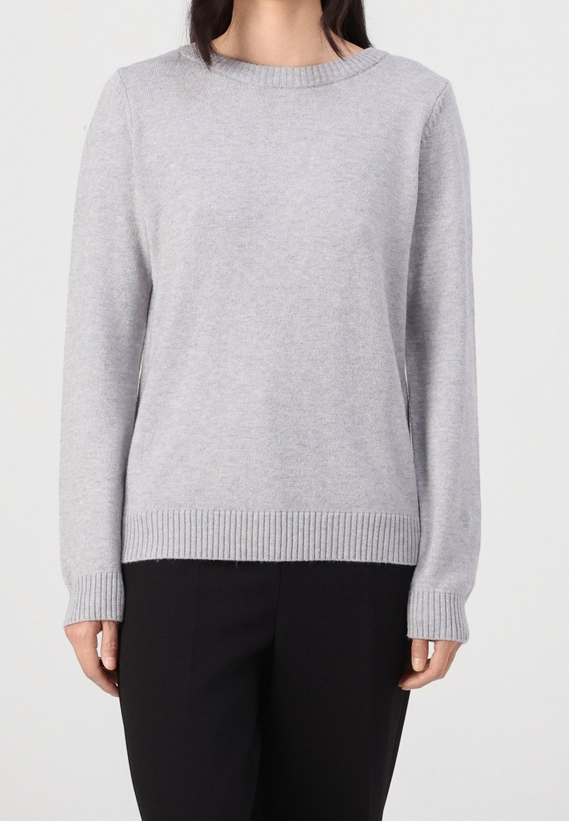 Light gray sweater made of soft knit material. Features a round neckline, ribbed cuffs, and hem, with long sleeves. Paired with black pants.