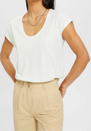 Hvid, kortærmet t-shirt med rund udskæring, lavet af letvægtsstof, kombineret med beige højttaljede bukser med forreste plissering og knaplukning.