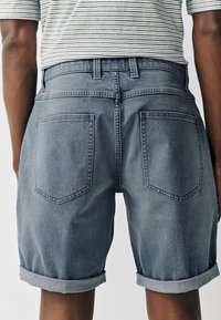 Hellblaue Jeansshorts mit aufgerolltem Saum, zwei Gesäßtaschen und klassischem Fünf-Taschen-Design mit sichtbaren Nähten.