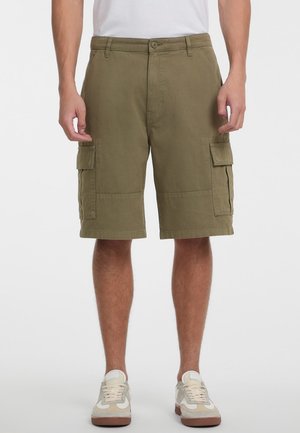 Olijfgroene cargoshorts met zijzakken, gemaakt van katoen. Heeft een knoopsluiting en een relaxte pasvorm. G gedragen met lichte sneakers.