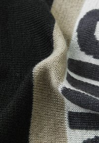Dzianina z czarnymi, kremowymi i szarymi paskami o teksturowej powierzchni; wyraźny wzór w ciemnoszarym kolorze.
