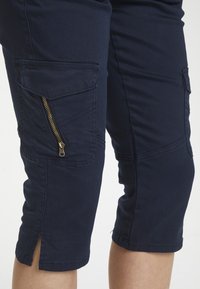 Marina cargo shorts med dragkedjeficka, knälängd, tillverkade av bomullstyg, med sidofickor och sydda detaljer.