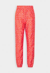 Pantalons à motif rouge avec un waistband élastique, jambes fuselées et un motif de logo répété en rose contrasté. Tissu lisse et léger.