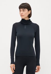 Maglietta nera a maniche lunghe con colletto alto, realizzata in un tessuto texturizzato, design aderente e maniche raglan per una maggiore libertà di movimento.