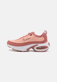 Sapatilha Nike em tons suaves de pêssego e rosa, com parte superior texturizada, silhueta curvada, sola acolchoada e detalhe de unidade de ar visível.