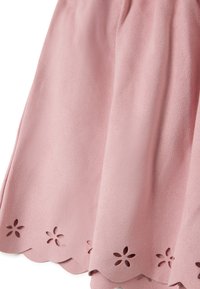 Falda rosa claro con una textura suave, que cuenta con un dobladillo en forma de pico y pequeños recortes de flores a lo largo del borde.