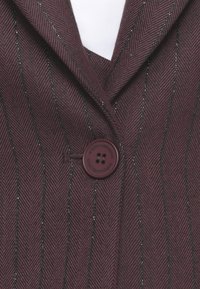 Blazer color mogano con un motivo a spina di pesce, caratterizzato da sottili riflessi di filo metallico, revers a punta e chiusura con bottone.