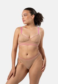 Bralette en slipset in nude met roze accenten. De bralette heeft dunne bandjes en een driehoekige vorm; de slip heeft een hoge uitsnede. Glad textuur.