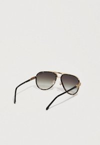 Gafas de sol con montura de metal dorado, acentos en negro y patrón de carey, y lentes grises degradados. Presentan almohadillas nasales ajustables.