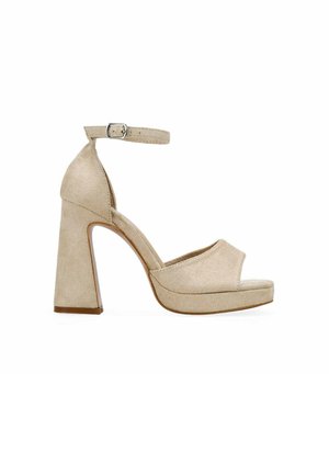 Sandalia de tacón alto de ante beige con correa en el tobillo, tacón ancho, punta abierta y suela con plataforma sobre fondo blanco.