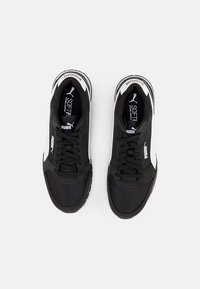 Scarpe da ginnastica nere con un upper testurizzato, accenti bianchi a contrasto sui lati e lacci. Presenta il branding sulla linguetta e sui lati.