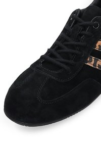 Schwarze Wildleder-Sneaker mit abgerundeter Zehenpartie, ausgestattet mit schwarzen Schnürsenkeln und einem Leopardenmuster-Akzent an den Seitenstreifen. Strukturiertes Material, leichtes Design.