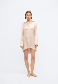 Cămașă de noapte din satin roz deschis, cu mâneci lungi, front cu nasturi, textură complicată și o margine ușor curbată pentru o potrivire relaxată.