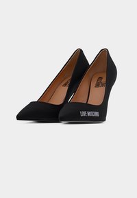 Ζευγάρι μαύρα ψηλοτάκουνα παπούτσια με μυτερή μύτη, με την επωνυμία "LOVE MOSCHINO" στο εξωτερικό μέρος και μπεζ εσωτερικές σόλες.