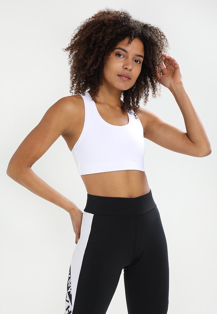 Hvit sports-bh med rund hals, tykke stropper og glatt tekstur; kombinert med høy-midje svarte leggings med en hvit panel på siden.