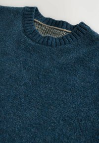 Pulover din lână bleumarin închis, cu guler reiat. Interiorul prezintă un model houndstooth mai deschis la culoare. Textură moale, cu aspect ușor pufoasă.