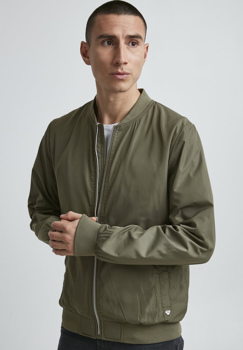 Olivegrüne Bomberjacke aus glattem, leichtem Material. Mit gerippten Bündchen und Kragen, Frontreißverschluss und Seitentaschen.