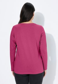 Koszulka z długim rękawem i okrągłym dekoltem w jednolitym, magentowym kolorze, wykonana z bawełny. Charakteryzuje się gładką fakturą i luźnym krojem, z minimalną ilością szwów i bez widocznych wzorów.