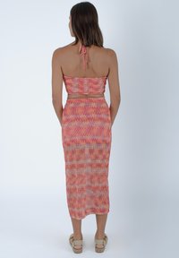 Completo a due pezzi composto da un top corto e una gonna lunga, realizzato in tessuto leggero e testurizzato con un motivo a zigzag nei colori rosa e arancione.