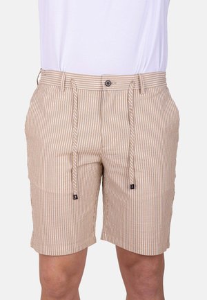 Pantalones cortos a rayas verticales beige y blancas con botón, cremallera, trabillas para el cinturón y cordones delanteros, usados con una camisa blanca.