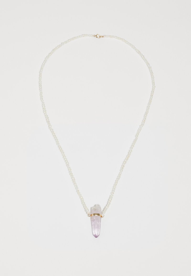 Halskæde med en række små perler og en spids krystalvedhæng, der skifter fra klar til lavendel, sikret med et guldbånd.