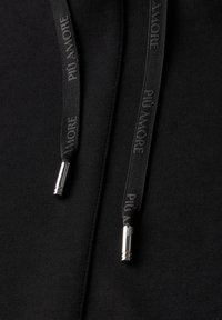 Sudadera negra con cordones planos que presenta el texto "PIÙ AMORE", terminales metálicos plateados y una textura suave. Diseño simple y minimalista.