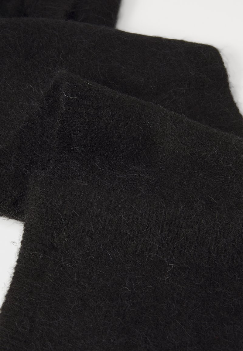 Écharpe en laine noire avec une surface douce et texturée. Le tissu semble dense et légèrement duveteux, avec des plis superposés visibles.