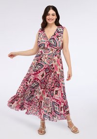 Rochie maxi cu decolteu adânc în V, fără mâneci, și un model geometric colorat în roz, albastru și crem. Material fluid și fustă în straturi.