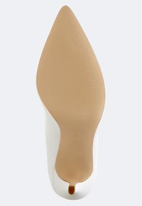 Chaussure à talon haut blanche avec un bout pointu et un matériau supérieur lisse. La semelle est en caoutchouc beige avec des motifs striés et un logo.