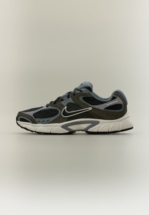 Μαύρο και γκρι παπούτσι τρεξίματος Nike με λευκή σόλα και λογότυπο, αεριζόμενα πάνελ από δίχτυ και επενδεδυμένο κολάρο, εμφανίζεται προφίλ σε ουδέτερο φόντο.