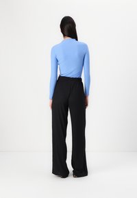 Ribbed long-sleeve top in light blue paired with loose black trousers. The outfit features a relaxed fit and an elastic waistband.