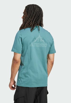 Turquoise cotton t-shirt featuring a geometric mountain design and "TERREX" text printed in white on the back. Short sleeves, standard fit.