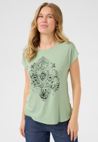 T-shirt vert clair à manches courtes, col rond, présentant un motif paisley noir sur le devant. Tissu doux et respirant.
