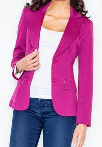 Fuksjowy żakiet o dopasowanym kroju, z wyłogami, na dwa guziki i kieszeniami z klapami. W zestawie z białą bluzką i ciemnymi dżinsami.