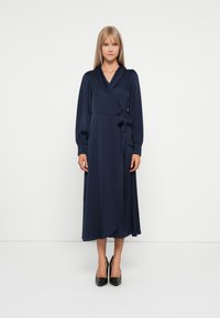 Navy blue wrap dress with long puff sleeves, waist tie detail, and a flowing skirt. Smooth fabric texture, knee-length design.