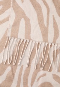 Beige og creme stofsjal med et zebra-print design; har franke kanter og en blød tekstur.