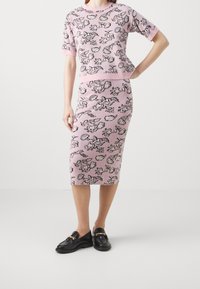 Gebreide twee-delige set in pastelroze met zwarte bloemen- en dierenpatronen. Korte mouwen top met geribde halslijn, aansluitende kokerrok.