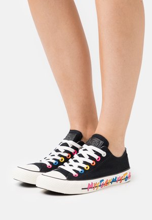 Sneakers neri in tela con suole in gomma bianche. Occhielli colorati e testo "LA MIA STORIA" stampato in rosa, blu e giallo sul lato.