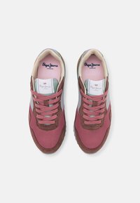 Sukellusvaaleanpunaiset verkkokengät ruskeilla ja harmailla yksityiskohdilla. Varustettu pehmustetulla kaulalla, kuudella vaaleanpunaisella nauhalla ja tekstuurilla varustetulla kumipohjalla. Brändin logo kengän kielellä.