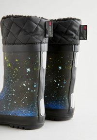 Bottes noires imperméables avec un motif de couleur dégradée composé de touches de vert, bleu et blanc, dotées d'un dessus matelassé et d'une semelle extérieure texturée.